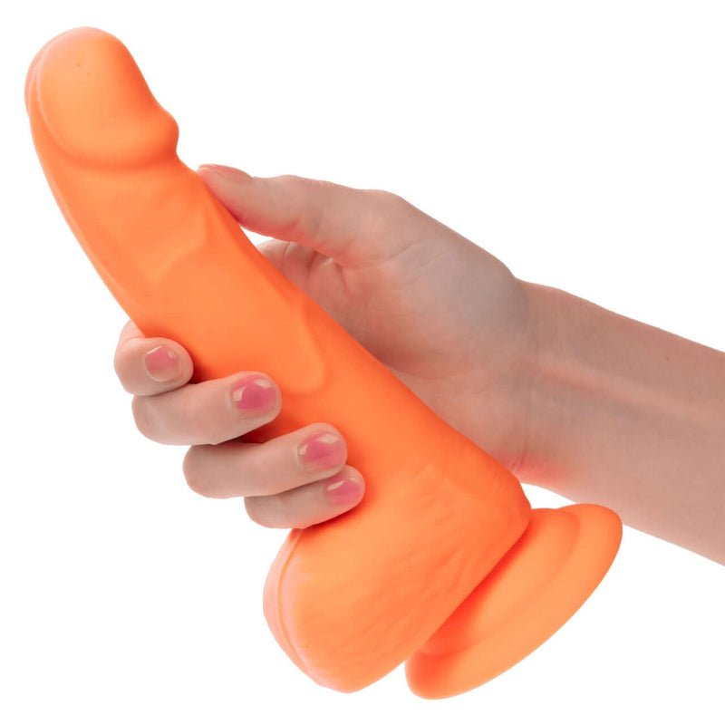 Hand holding Neon Silicone Studs 6 Inch Orange, lifelike and vibrant pleasure toy