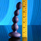 Evolved Pleasure Orbit Remote Control Vibrating Bulbed Shaft next to a measuring tape showing size dimensions against a blue background