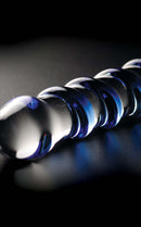 Icicles No 5 Textured Glass Dildo 7.25 inch Clear Blue artfully displayed on a dark surface, showcasing its elegant design.