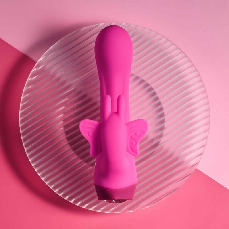 Selopa Butterfly Love powerful petite vibrator with curved shaft on a clear glass plate and pink background