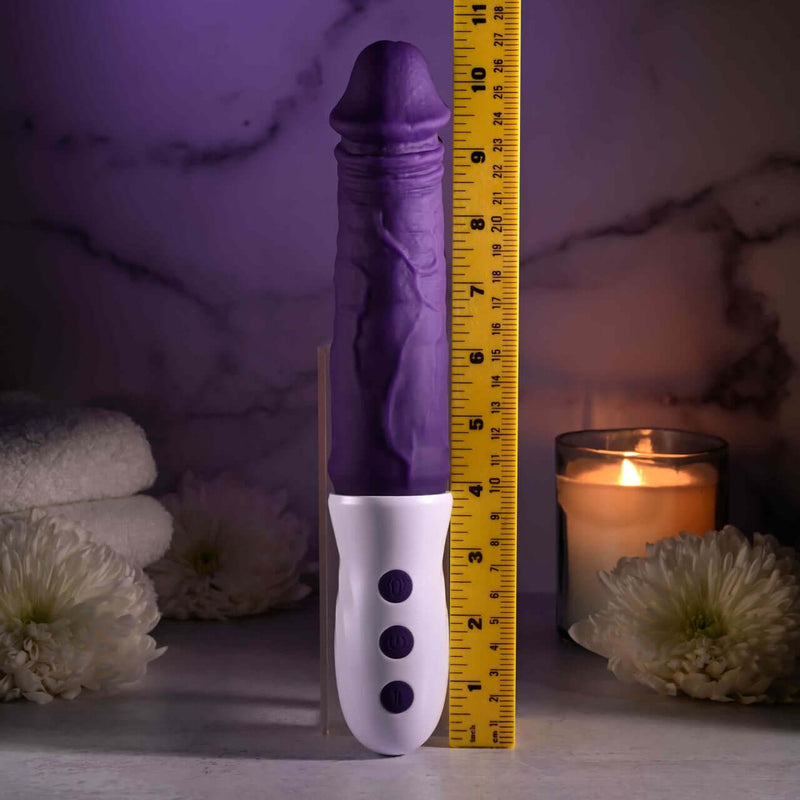 EVOLVED Plum Thrust realistic thrusting vibrator with ruler for scale, showcasing 1.5 inches thrusting capability, candlelight background
