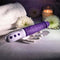 EVOLVED Plum Thrust realistic thrusting vibrator in a serene setting with flowers and candle.
