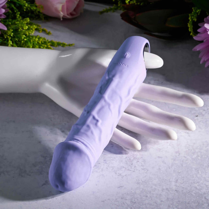 Evolved Purple Fantasy Vibrator with realistic veins and textures held in a white mannequin hand, featuring a chrome-finished ring handle.