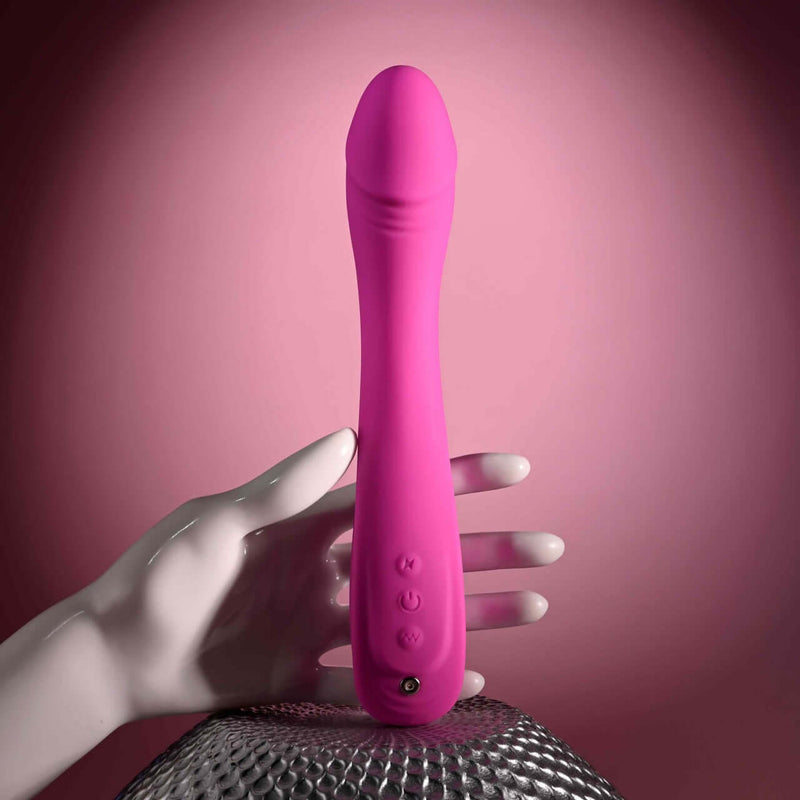 Pink Evolved Sugar Rush G-Spot Vibrator with multi-speed settings held by a white mannequin hand on a textured surface