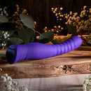 Selopa Trixxxie Vibrator on wooden surface, flexible and textured shaft, purple color, floral background, 7 vibration modes, USB rechargeable
