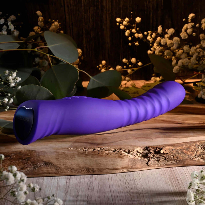 Selopa Trixxxie Vibrator on wooden surface, flexible and textured shaft, purple color, floral background, 7 vibration modes, USB rechargeable