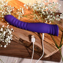 Selopa Trixxxie Vibrator USB charging on wooden surface, surrounded by flowers