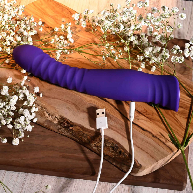 Selopa Trixxxie Vibrator USB charging on wooden surface, surrounded by flowers