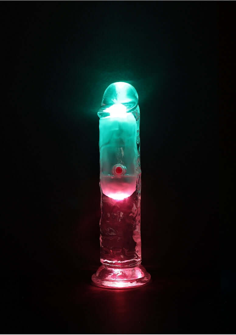 RealRock Rechargeable Dildo with Remote Control 6 inches, illuminated in vibrant colors, showcasing its realistic design.