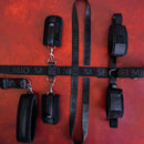 SEI MIO Seated & Mistreated Unique Under Chair Restraint System shown on a red background with straps and cuffs.
