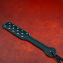 Sei Mio Studdy Hard Punishment Paddle With Metal Studs on a red background showcasing its design and texture.