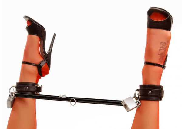 Black steel spreader bar with fettered legs in high heels, emphasizing BDSM and fetish exploration.