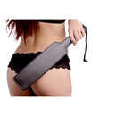 Strict Leather Black Fraternity Paddle held by a model in lingerie, showcasing its classic impact play design.