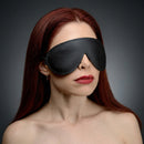 Strict Leather Padded Blindfold worn by a model, featuring a sleek black leather design for sensory play.