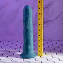 Realistic Evolved Tsunami Vibrator with textured shaft and remote, shown with measuring tape for size comparison on tiled surface