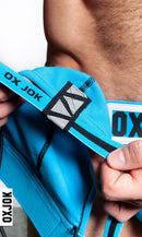 Oxjok Slingjock Upthrust Slider-Strap Jock Pool XL being held, showcasing its blue strap and logo details.