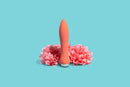 Sensuelle 60SX Amp Silicone Bullet Vibrator in Coral placed between pink flowers on a blue background