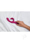 A hand adjusting the We Vibe Nova 2.0 pink rabbit vibrator on a white sheet.