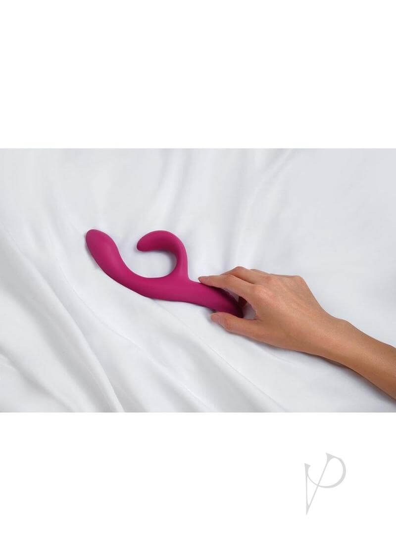 A hand adjusting the We Vibe Nova 2.0 pink rabbit vibrator on a white sheet.