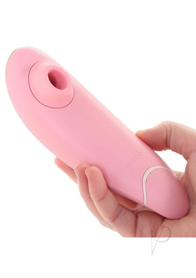 Pink Womanizer Premium Eco with biodegradable Biolene, held in hand, features innovative Pleasure Air Technology for clitoral stimulation.