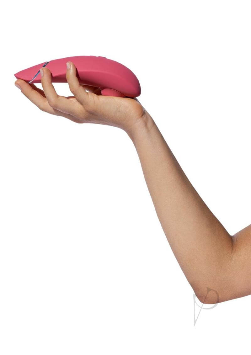 Hand holding Womanizer Premium 2 Raspberry luxury toy with innovative features and 14 intensity levels for a guided, sensory experience