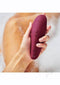 Woman holding Womanizer Classic 2 Bordeaux with silky-smooth surface and 10 intensity levels in a relaxing bath setting.