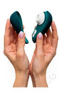 Hands holding Womanizer LIBERTY 2 in Dark Petrol with hygienic magnetic cover. Portable pleasure companion for travel.