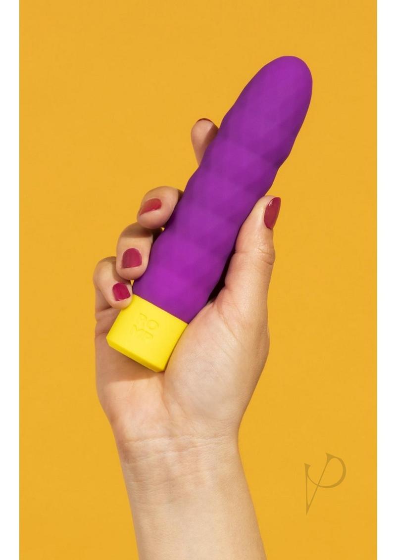 Person holding the ROMP Beat Purple bullet vibrator against a yellow background