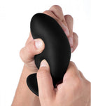 Close-up of a person squeezing a large black Squeeze It Silexpan anal plug, showcasing its flexible design and texture.