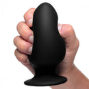 Large black squeezable anal plug being held in hand, showcasing its flexible design and tapered shape.