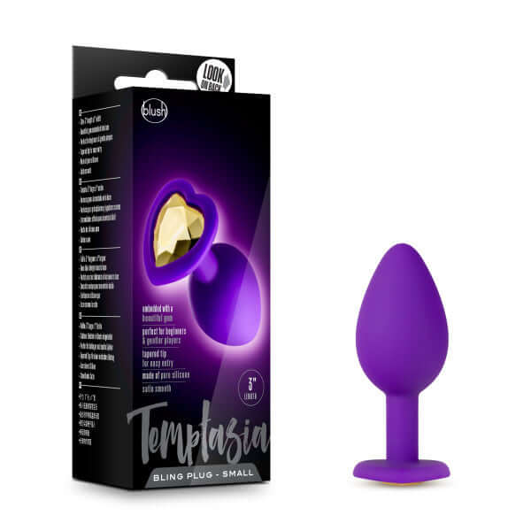 Temptasia Bling Plug Small Purple with heart-shaped base and gold faux gemstone, body jewelry by Blush Novelties in box and displayed.