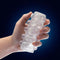 Hand holding Rize Swich Glow In The Dark Self Lubricating Stroker Clear from Blush Novelties with soft ticklers and ribbed inside.