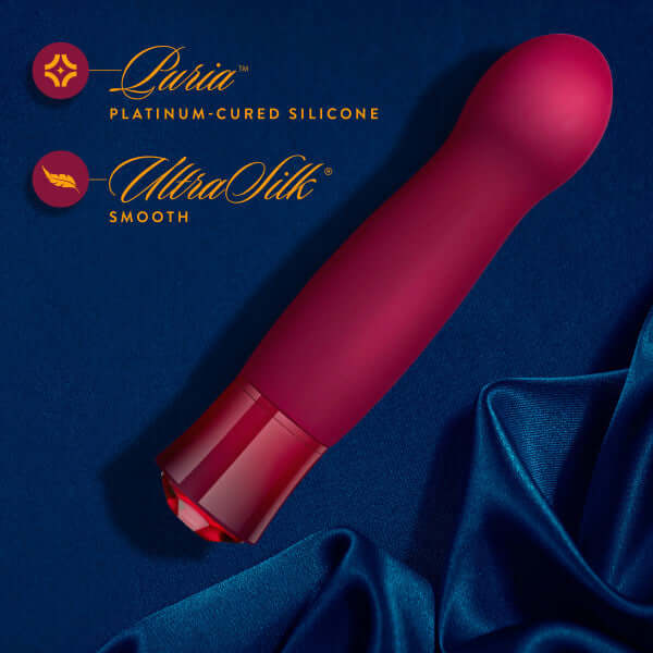 Oh My Gem Classy Garnet Red Vibrator with rounded end on blue fabric, showcasing Luxuria platinum-cured silicone and Ultrasilk smooth finish