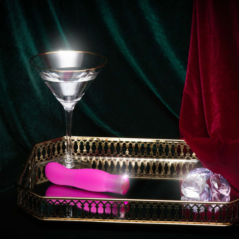Pink Oh My Gem Exclusive Tourmaline Vibrator displayed on elegant tray with glass and gems