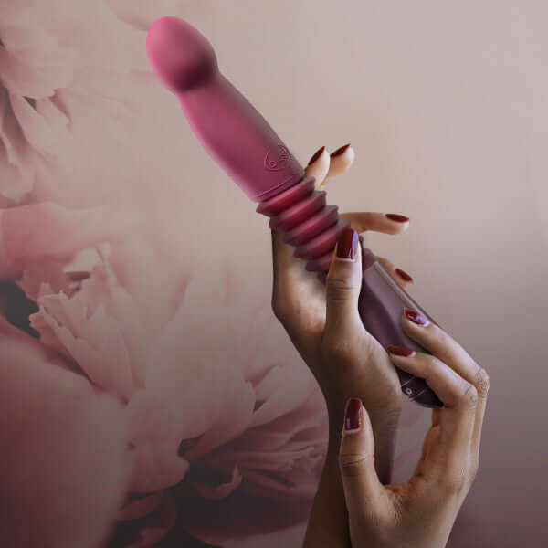 Woman holding the Temptasia Trixie Thrusting Dildo from Blush Novelties in a floral background.