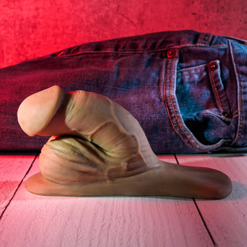 Gender X 4 inches dark skin tone packer dildo with lifelike design and jeans in the background