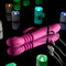 Pink Dragon Rabbit Vibrator on a reflective surface surrounded by colorful LED candles, showcasing its USB charging feature.