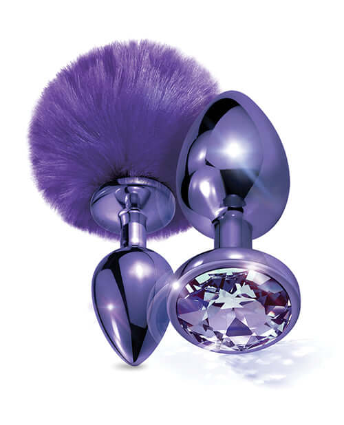 Nixie Metal Butt Plug Set with purple pom pom tail and faux jewel, featuring sleek metal finish and tapered design.