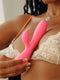 Woman holding the pink JimmyJane Glo Rabbit Heating Vibrator near her chest while wearing lace lingerie.