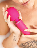 Woman holding the vibrant pink JimmyJane Exona Body Wand in a relaxing setting.