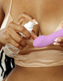 Woman applying JimmyJane Toy Lubricant on a purple adult toy for enhanced intimate pleasure.