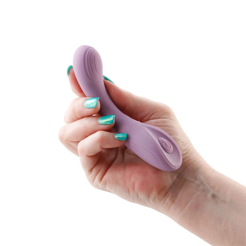 A hand holding the Desire Pure Dusty Lavender Vibrator, showcasing its petite design and soft texture.