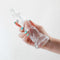 Hand holding the Fantasia Siren Clear Dildo, renowned for luxurious pleasure and performance excellence by NS Novelties.