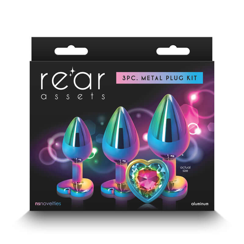 Rear Assets Rainbow Heart Trainer Kit packaging with three chrome-plated anal plugs in graduated sizes, adorned with heart-shaped gems.