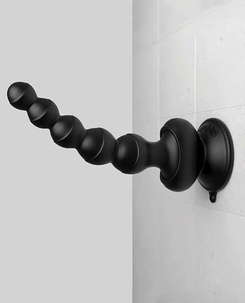 Threesome Wall Banger Beads vibrating massager with suction cup base attached to a tiled wall.