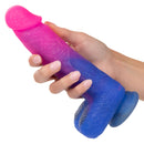 Person holding Naughty Bits Ombre Hombre XL Vibrating Dildo with pink, purple and blue glitter finish from California Exotic Novelties