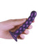 Beaded metallic purple silicone G-spot dildo with suction cup base held in hand.