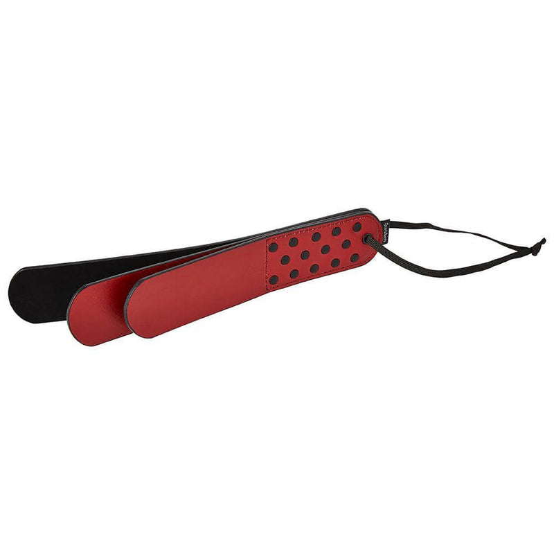 Sportsheets Saffron Layer Paddle in red and black vegan leather, designed for impact play with polka dot detailing.