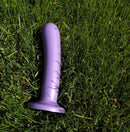 Silk Large Purple Haze Dildo from Tantus Silicone lying on grass.