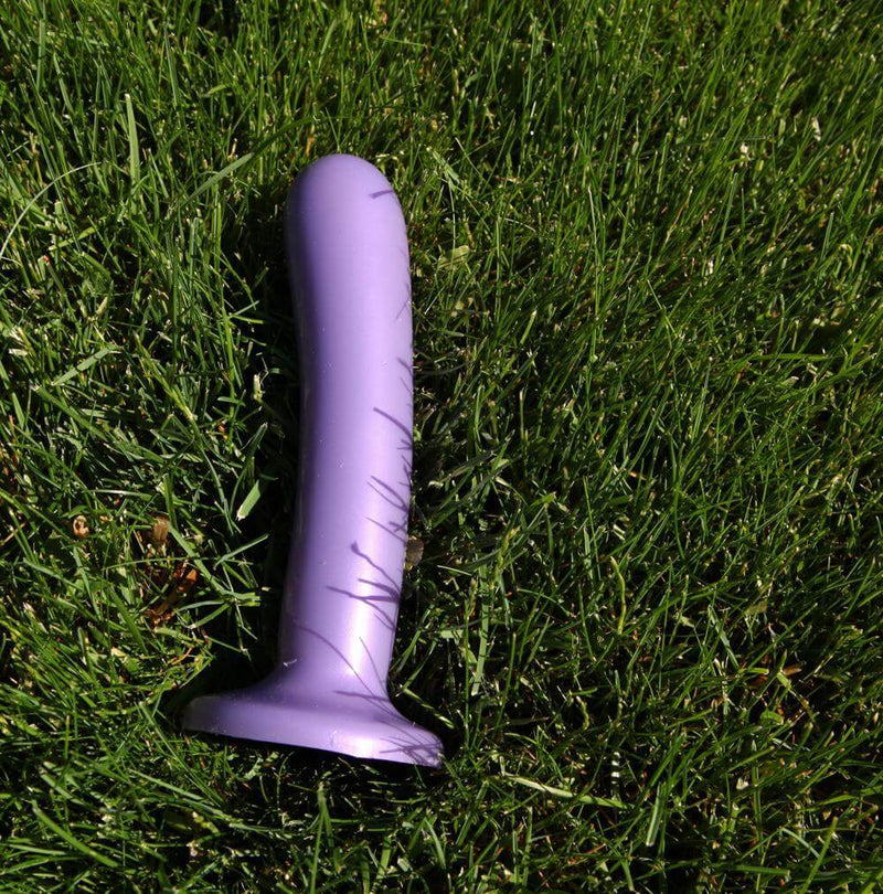 Silk Large Purple Haze Dildo from Tantus Silicone lying on grass.